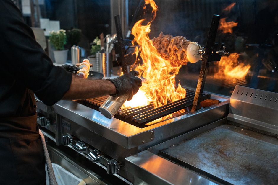 Kuhar grilira meso s plamenom u kuhinji